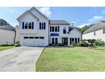 Charming two-story home featuring a well-manicured lawn, white painted brick, and a two-car garage at 9440 Knollcrest Blvd, Alpharetta, GA 30022