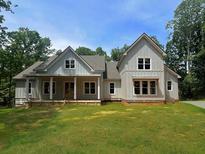 Beautiful new construction home with light gray vertical siding, complemented by a lush green lawn and charming front porch at 2200 Upper Burris Rd, Canton, GA 30114
