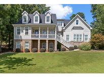 Inviting two-story home featuring a charming front porch, dormer windows, and lush landscaping at 5178 Stefan Ridge Way, Buford, GA 30519