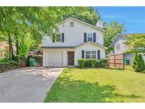 Charming two-story home with a well-manicured lawn and attached garage, framed by mature trees at 912 Third St, Stone Mountain, GA 30083