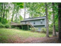 Exterior view of a single Gathering home with a deck surrounded by mature trees and lush greenery at 4190 Heather Way, Cumming, GA 30041