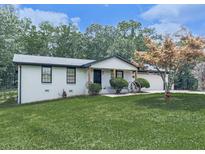 Charming one-story home features a white brick exterior, manicured lawn and mature trees at 464 Mason Dr, Canton, GA 30115