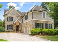 Charming two-story brick home with manicured landscaping, a two-car garage, and a welcoming stone-accented entrance at 2700 Vinings Orchard Cir, Atlanta, GA 30339