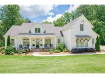 Beautiful modern farmhouse with a well-manicured lawn, covered porch, and professionally landscaped yard at 124 White Oak Trl, Cumming, GA 30028