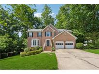 Charming two-story brick home featuring an attached two-car garage, manicured lawn, and mature trees at 1679 Summit Place Way, Loganville, GA 30052