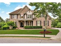 Elegant brick home with lush lawn, manicured landscaping, and welcoming front porch at 1231 Ellington Ct, Cumming, GA 30041