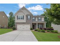 Charming two-story home featuring a brick facade, well-manicured lawn, and attached two-car garage at 6240 Vista Crossing Way, Cumming, GA 30028