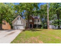 Charming two-story home features a well-manicured lawn, attached two car garage, and mature landscaping at 3470 River Mill Ln, Ellenwood, GA 30294