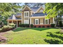 Charming two-story home featuring manicured lawn, brick accents, and complemented by mature trees at 4711 Oakleigh Manor Dr, Powder Springs, GA 30127