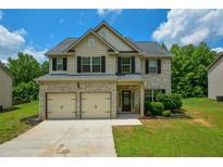 Charming two-story home features a brick facade, two-car garage and lush green lawn at 917 Revere Way, Hampton, GA 30228