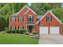 Charming two-story brick home with a well-manicured lawn, a basketball hoop, and a two-car garage at 135 Clubhouse Nw Dr, Kennesaw, GA 30144