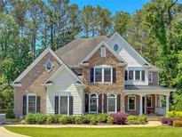 Charming home boasts a combination of brick and stone, complemented by a lush lawn and mature trees at 1575 Petal Nw Pt, Kennesaw, GA 30152