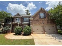 Charming brick home with a two-car garage, manicured lawn, and beautiful landscaping at 381 Plymstock Dr, Mcdonough, GA 30253