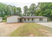 Charming one-story white brick home with a well-manicured lawn and mature trees at 703 Alvis Ln, Norcross, GA 30093