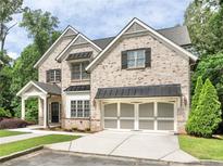 Charming two-story brick home featuring manicured lawn, black shutters, and a convenient two-car garage at 1300 Winfair Ne Ln, Brookhaven, GA 30329