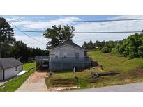 Cozy home featuring a deck, mature trees, and a unique carport underneath the rear of the house at 380 South St, Buford, GA 30518
