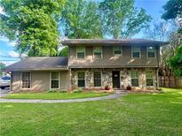 Charming two-story home with stone accents, manicured lawn, and lush trees at 4506 Town Crier Sw Rd, Lilburn, GA 30047