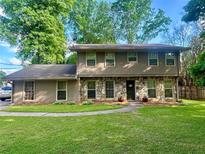 Charming two-story home featuring stone accents, a well-manicured lawn, and mature trees at 4506 Town Crier Sw Rd, Lilburn, GA 30047