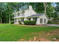 Charming white home featuring a double-decker balcony, lush lawn, and mature trees at 5290 River Mill Cir, Marietta, GA 30068