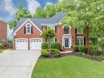 Charming two-story red brick home boasts a three-car garage and lush landscaping at 10400 Groomsbridge Rd, Alpharetta, GA 30022