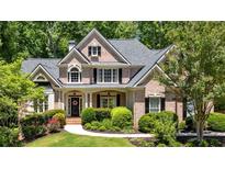 Beautiful two-story brick home featuring a landscaped front yard with lush green trees at 1311 Cobblemill Nw Way, Kennesaw, GA 30152
