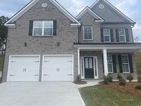 Two-story home with gray brick, black shutters, a two-car garage, and a covered front entrance at 1678 Lacebark Elm Way Way, Lawrenceville, GA 30045