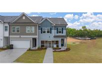 Charming two-story townhome featuring a manicured lawn, attached garage, and craftsman-style details at 1019 Merritt Dr # 102, Villa Rica, GA 30180