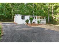 Charming home with a covered front porch, dark shutters, and an asphalt driveway surrounded by lush trees at 4212 Bryan Se Dr, Acworth, GA 30102