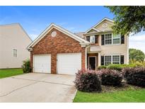 Two-story home with brick and siding, a two-car garage, and manicured landscaping at 11576 Kades Trl, Hampton, GA 30228