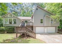 Two-story home featuring wood and siding exterior, multi-car garage, and an elevated wooden front porch and entry at 2071 Arrowhead Trl, Marietta, GA 30062