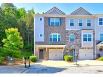 Charming townhome showcases a well-maintained exterior with gray brick, complementary siding and a single car garage at 1005 Belfry Ter, Fairburn, GA 30213