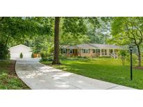 Charming brick home with a long driveway, well-manicured lawn, and a detached garage, surrounded by lush greenery at 5401 Rosser Rd, Tucker, GA 30087