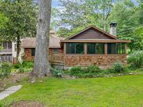 Charming bungalow with wood shingles, stone chimney, screened porch, and mature trees at 4624 Park Dr, Pine Lake, GA 30072