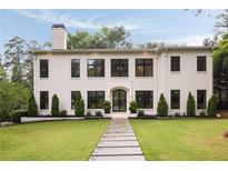 Modern two-story home featuring a manicured lawn, symmetrical landscaping, and dark-trimmed windows at 4132 Carmain Ne Dr, Atlanta, GA 30342