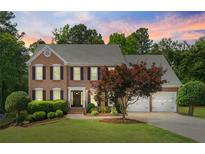 Charming two-story brick home featuring a landscaped yard, two-car garage, and classic architectural details at sunset at 1661 Duxbury Nw Ln, Kennesaw, GA 30152