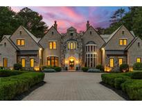 Stunning stone and brick home featuring a circular driveway, manicured landscaping, and elegant architectural details at 4560 Harris Trl, Atlanta, GA 30327