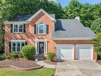 Charming two-story brick home with a well-manicured front yard and two-car garage, surrounded by mature trees at 2346 Unicoi Ct, Duluth, GA 30097