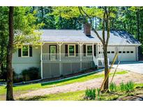 Charming home featuring a welcoming front porch, a two-car garage, and mature trees at 6026 Belle Meade Ct, Villa Rica, GA 30180