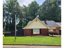Charming brick home with a well-manicured lawn, black fence, and mature landscaping at 6210 Douglas Manor Ct, Douglasville, GA 30134