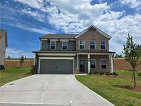 Two-story home featuring a brick and siding facade, two-car garage and concrete driveway at 702 Bristol Dr, Loganville, GA 30052