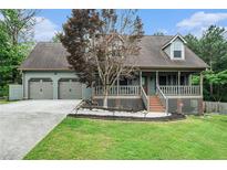 Charming home featuring a covered porch, two-car garage, and manicured lawn at 1235 Waterwood Dr, Loganville, GA 30052