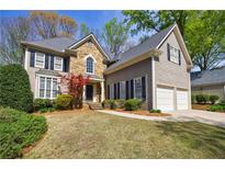 Charming two-story home featuring a stone facade, manicured lawn, and a two-car garage at 1021 Oakpointe Pl, Dunwoody, GA 30338