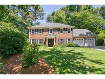 Charming two-story brick home features a well-manicured lawn, mature trees, and a three-car garage at 1850 Linnet Ne Ct, Roswell, GA 30075