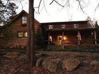 Inviting rustic log home featuring a cozy front porch and a beautifully wooded setting at 6965 Flowery Branch Rd, Cumming, GA 30041
