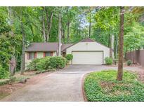 Charming single-story home with a well-maintained lawn and a two-car garage surrounded by lush trees at 2174 Kinridge Rd, Marietta, GA 30062