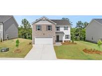 Charming two-story home featuring a brick facade, attached two-car garage, and well-manicured front lawn at 613 Lobelia Way, Locust Grove, GA 30248