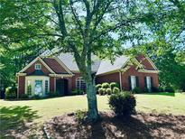 Charming brick home boasts mature trees, manicured lawn, and inviting curb appeal at 6605 New Ridge Court Ct, Cumming, GA 30041