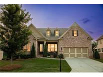 Charming brick home featuring a manicured lawn, dormer windows, and a spacious two-car garage at 2665 Crowbrook Way, Cumming, GA 30040