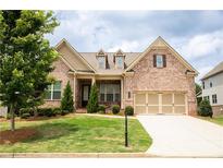 Beautiful brick home with a well-manicured lawn, mature tree, and charming architectural details at 2665 Crowbrook Way, Cumming, GA 30040
