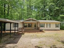 Inviting single-story home with a cozy front porch, carport, and neutral siding surrounded by lush trees at 85 Holly Dr, Carrollton, GA 30116